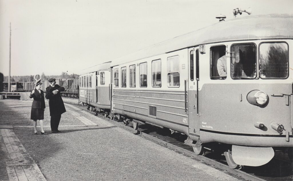 Lättähattu odottamassa lähtöä Heinolan rautatieasemalla 1968. Junanlähettäjä katsoo kelloa.