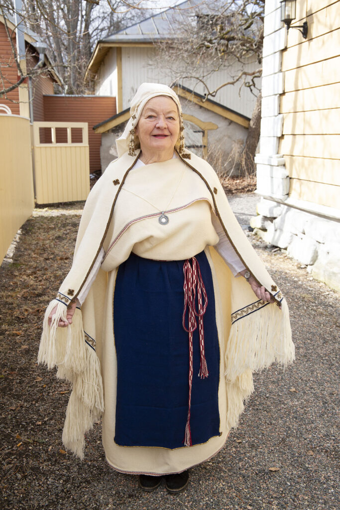 Kuva vanhemmasta rouvasta pukeutuneena valkoiseen Perniön pukuun. Kuvan ottanut Silvi Kaarakainen.