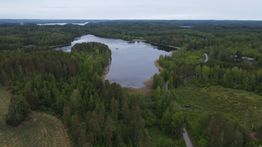 Ilmakuva Merjeslammesta. Kuvan keskellä vesistö, etu- ja taka-alalla vihreää metsää, vasemmassa etureunassa peltoa.